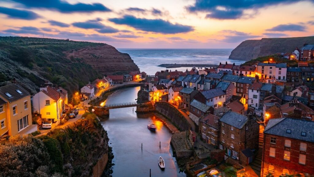 Staithes at dusk, harbour lights reflected in the beck below the cliffs.