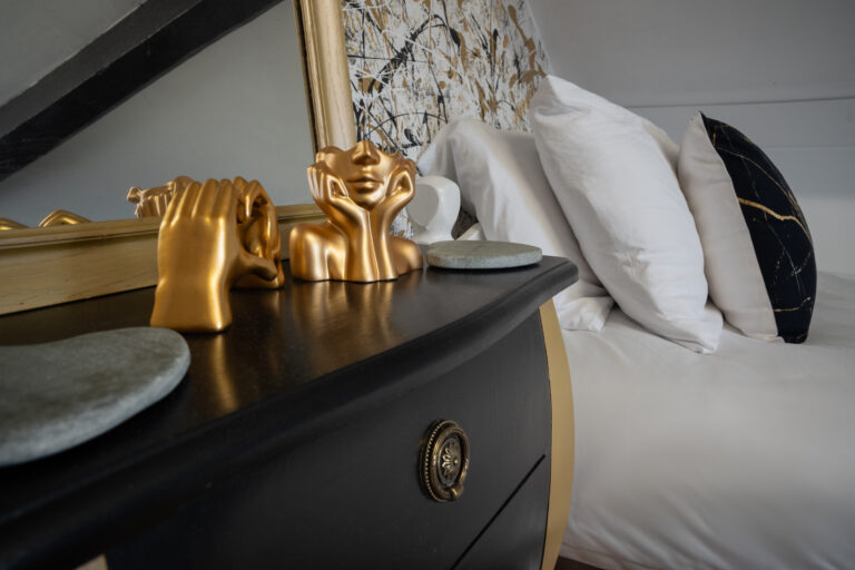 Gold ornaments on a black dresser beside white pillows in the loft room.