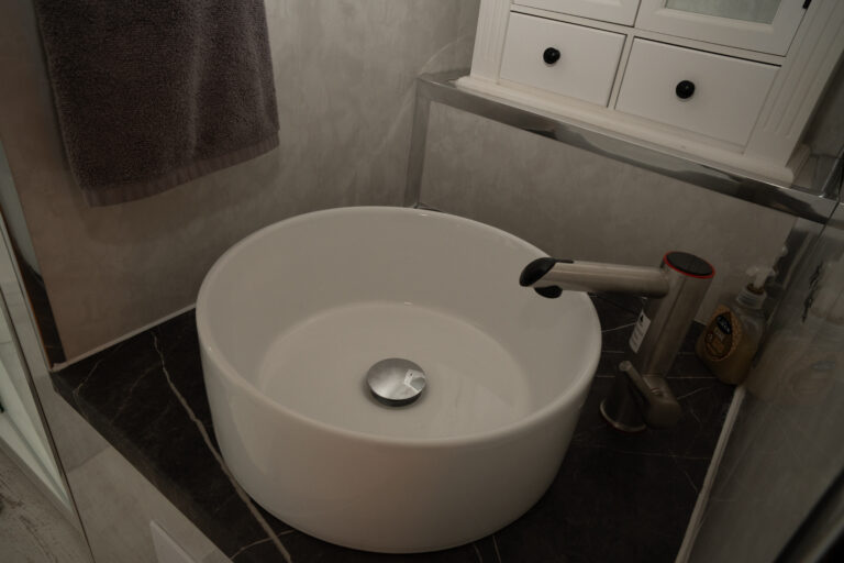 Round countertop basin with a black tap.