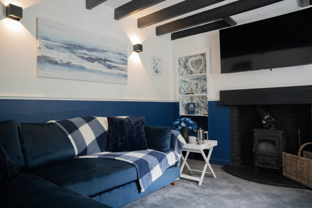 Living room with a log burner and a checked sofa against navy panelling.
