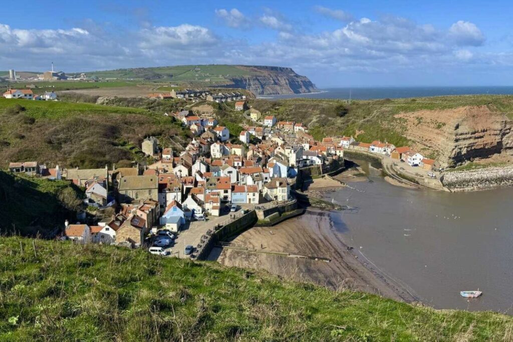 Staithes seen from the Cleveland Way cliff path: red roofs, the harbour and the beck below, sea and headland beyond.
